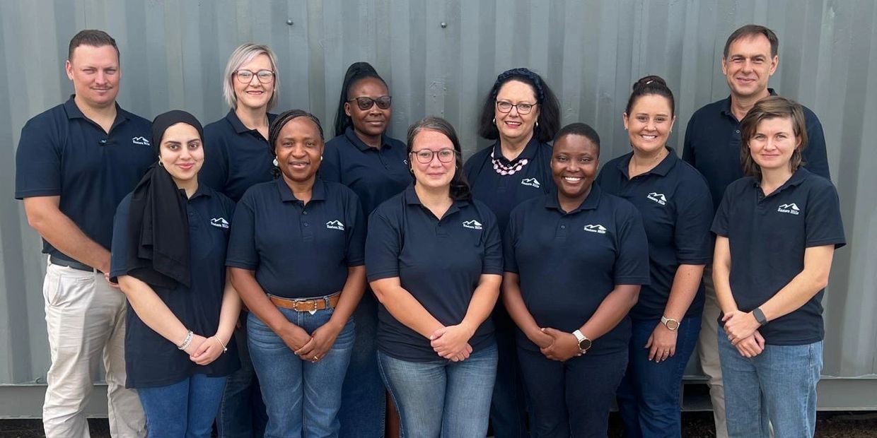 Diverse team wearing matching navy blue polo shirts standing together, smiling.