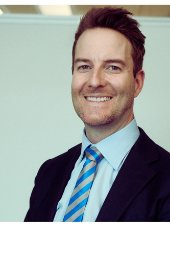 Smiling man in a suit with a striped blue tie.