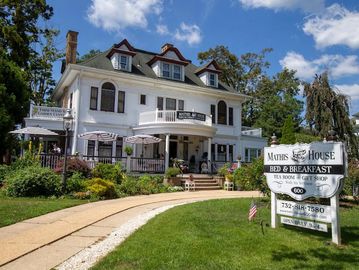 Elegant white bed and breakfast house with outdoor seating.