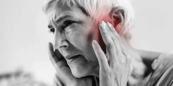 person holding their head with a headache because of  painful ears and blocked ears