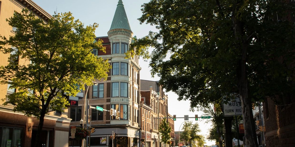 Historic building with a green spire on a sunny city street.