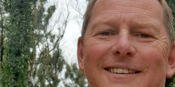 Close-up of a smiling man outdoors.