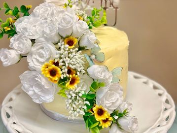 Elegant cake adorned with white and yellow flowers.