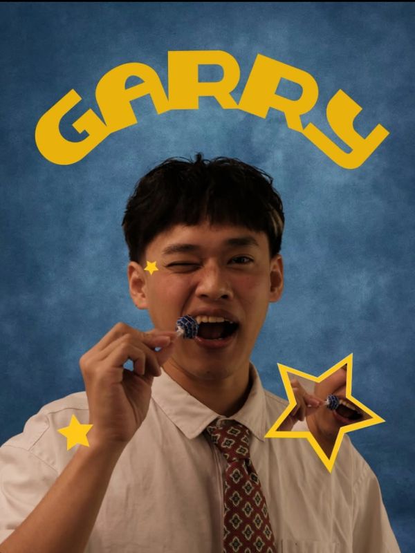 一名男子眨眼吃棒棒糖，名字“GARRY”在头顶。