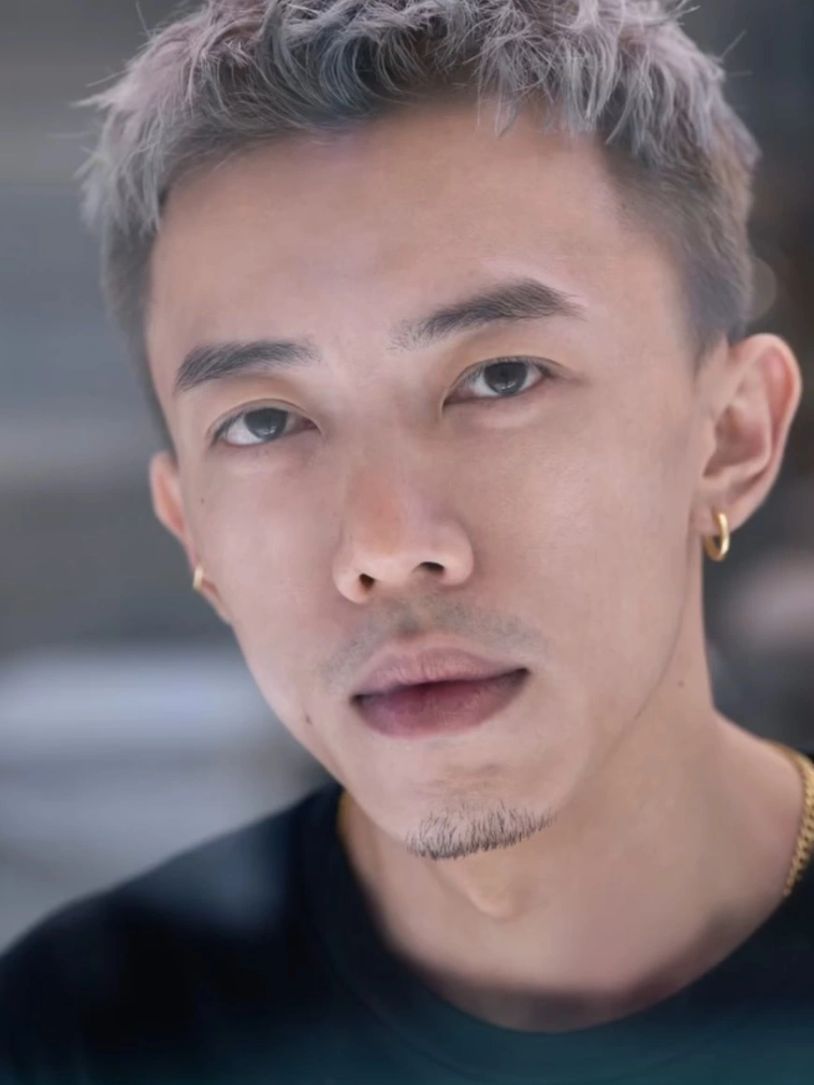 年轻男子的特写肖像，有银色短发和耳环。