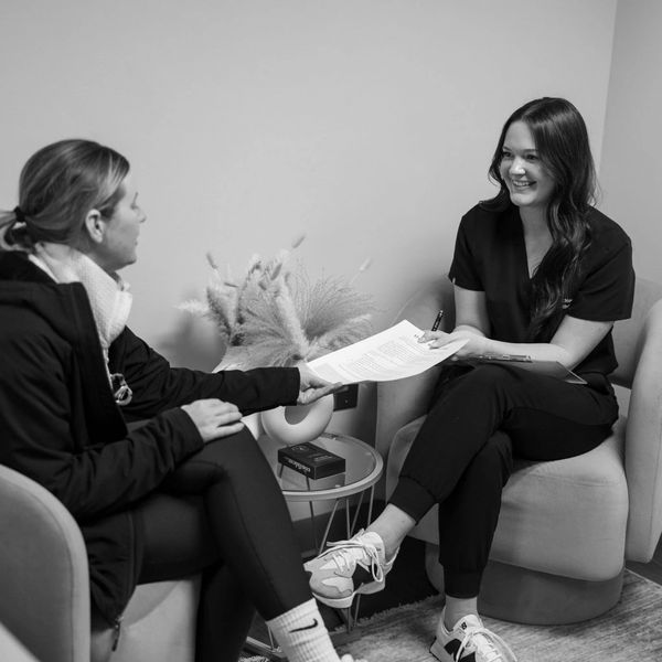 Two women in a friendly consultation exchanging documents in a cozy office.