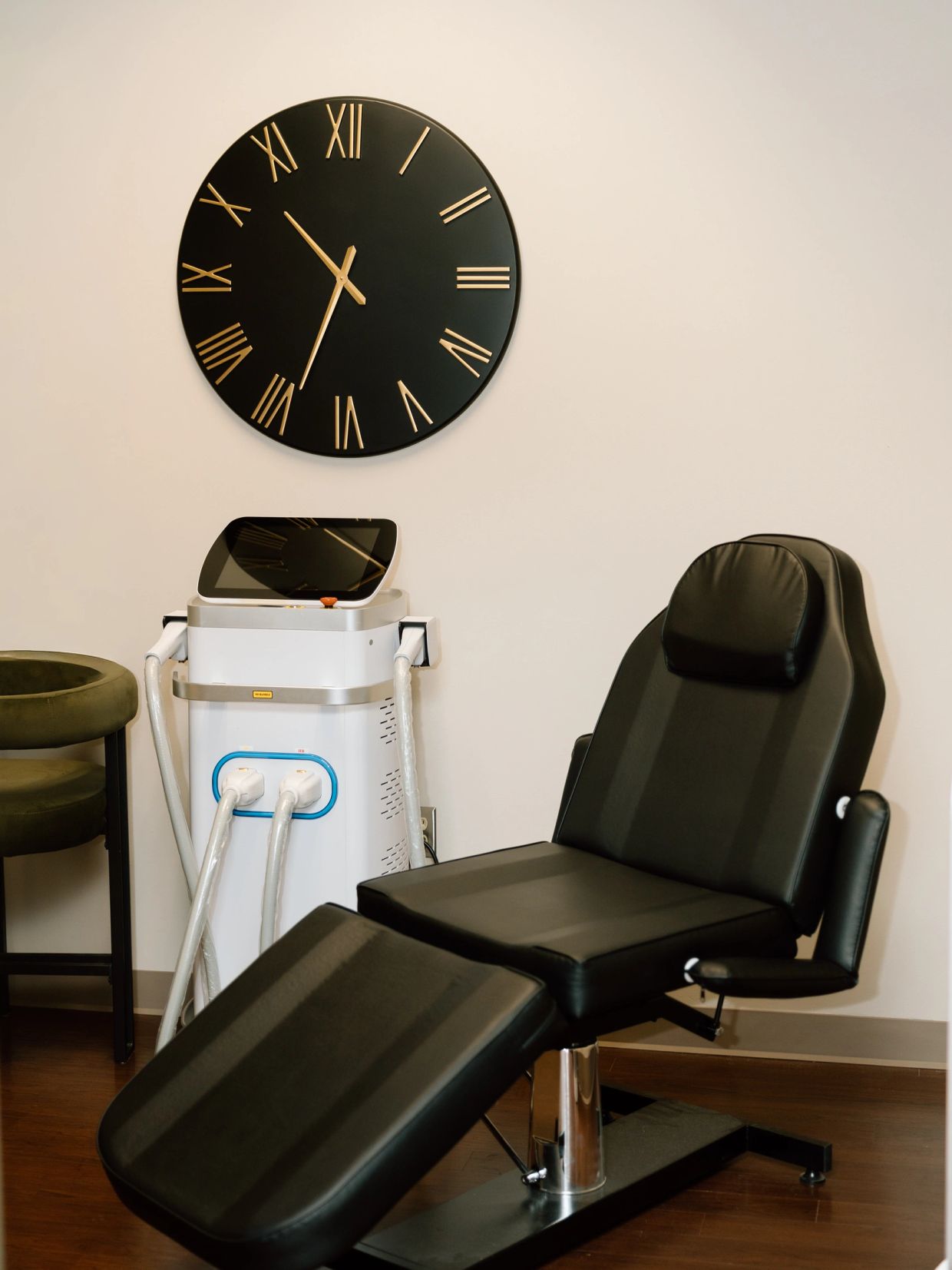 A modern black reclining chair and a large wall clock in a clinical room.