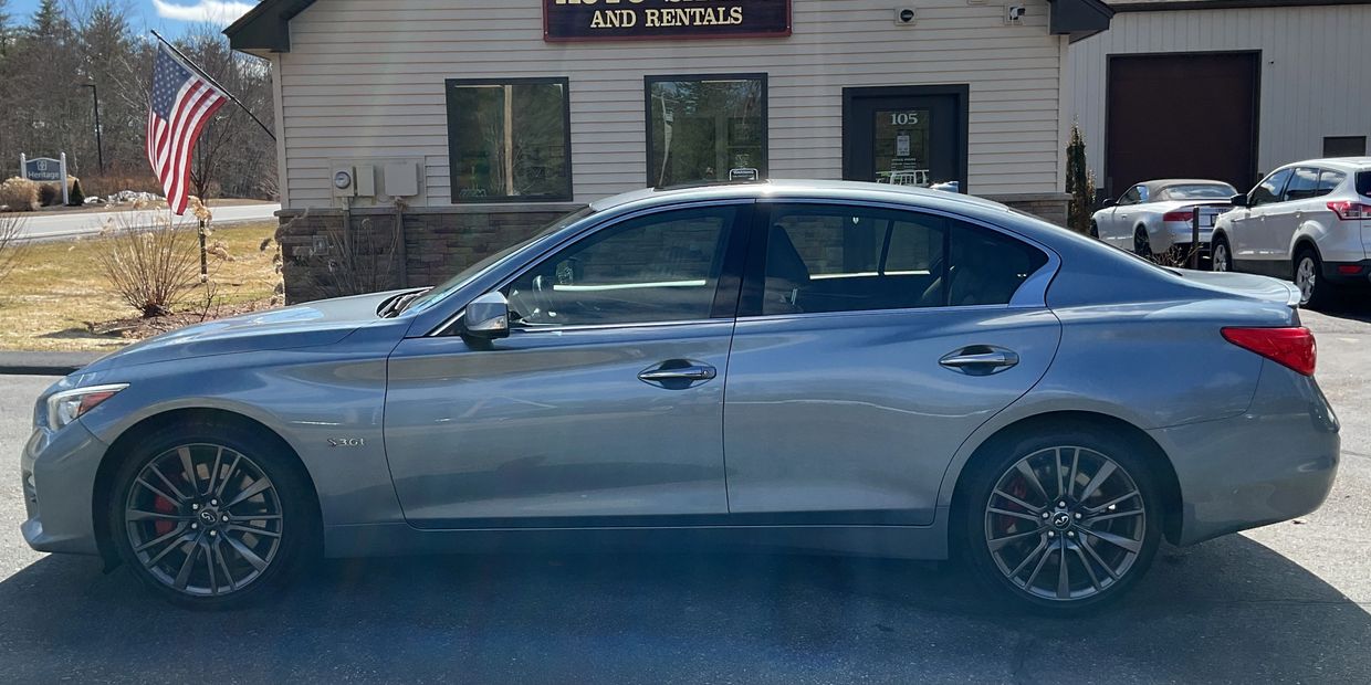 Side view of a sleek gray Infiniti Q50 sedan parked outside a building.