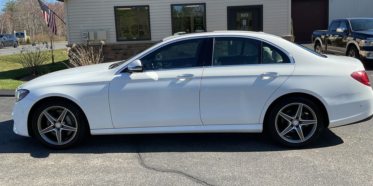 White luxury sedan parked outside a building on a sunny day.