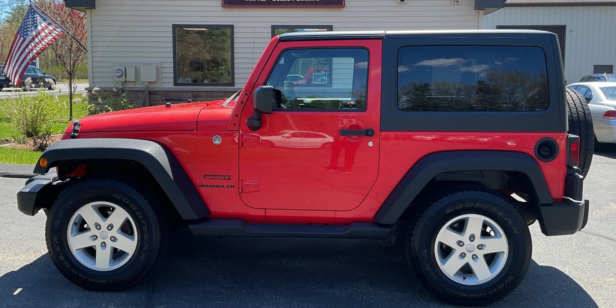 Red Jeep Wrangler Sport parked outside on a sunny day.