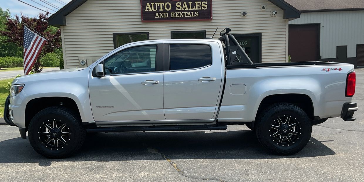White 4x4 pickup truck parked in front of an auto sales and rentals building.