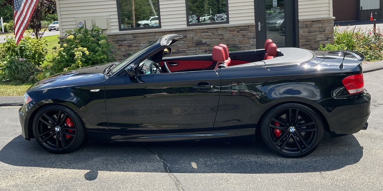 Black BMW convertible with red interior parked outdoors.