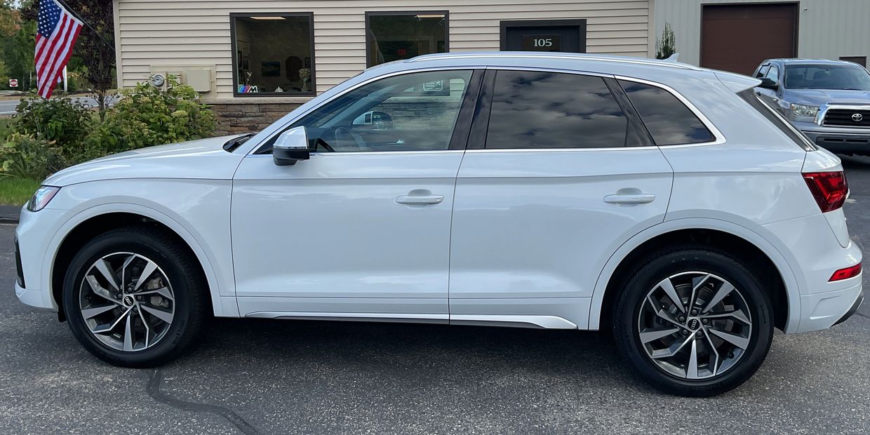 Side view of a white Audi SUV parked outside a building.