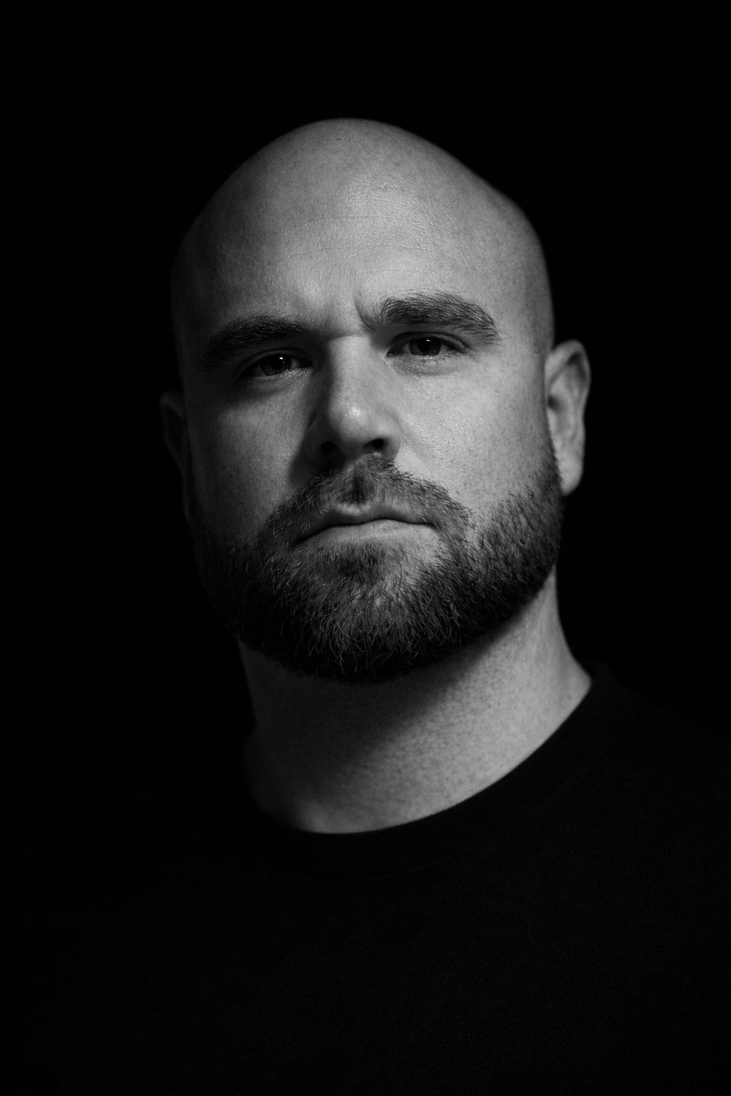 Man with stern look in a black shirt with a black backdrop