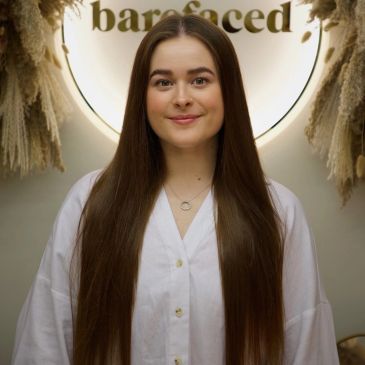 Woman with long straight hair in white shirt smiling.