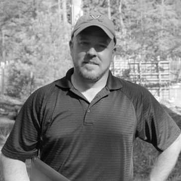 Man standing outdoors in a cap and polo shirt.