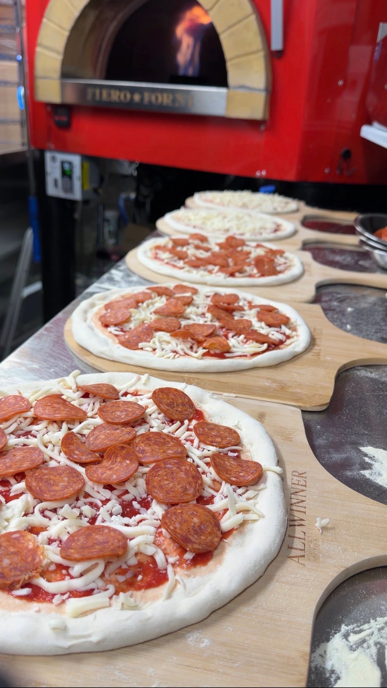 Pepperoni pizzas ready to bake in a wood-fired oven.