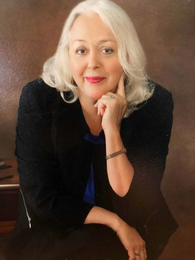 Elegant older woman with white hair in a thoughtful pose.