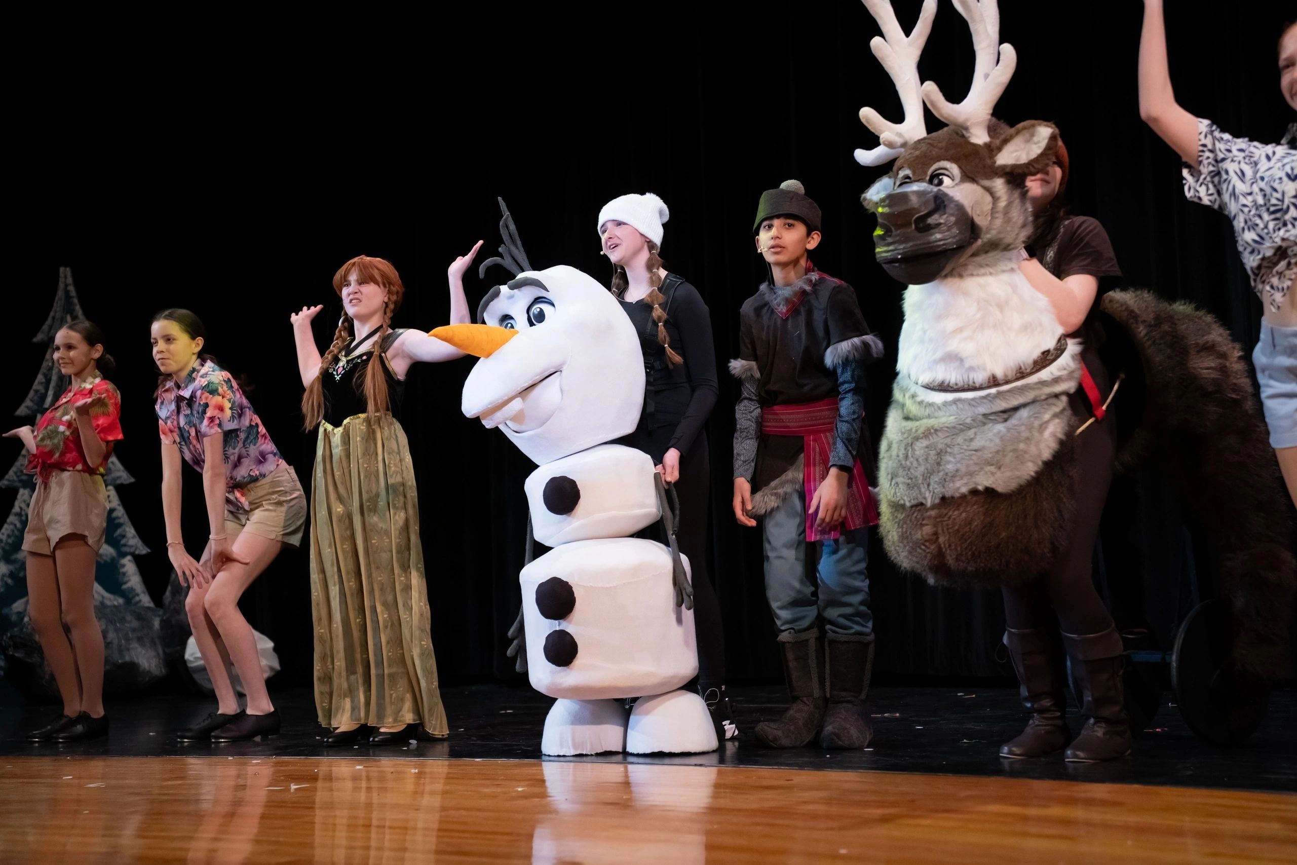 Children performing in a Frozen-themed play on stage.