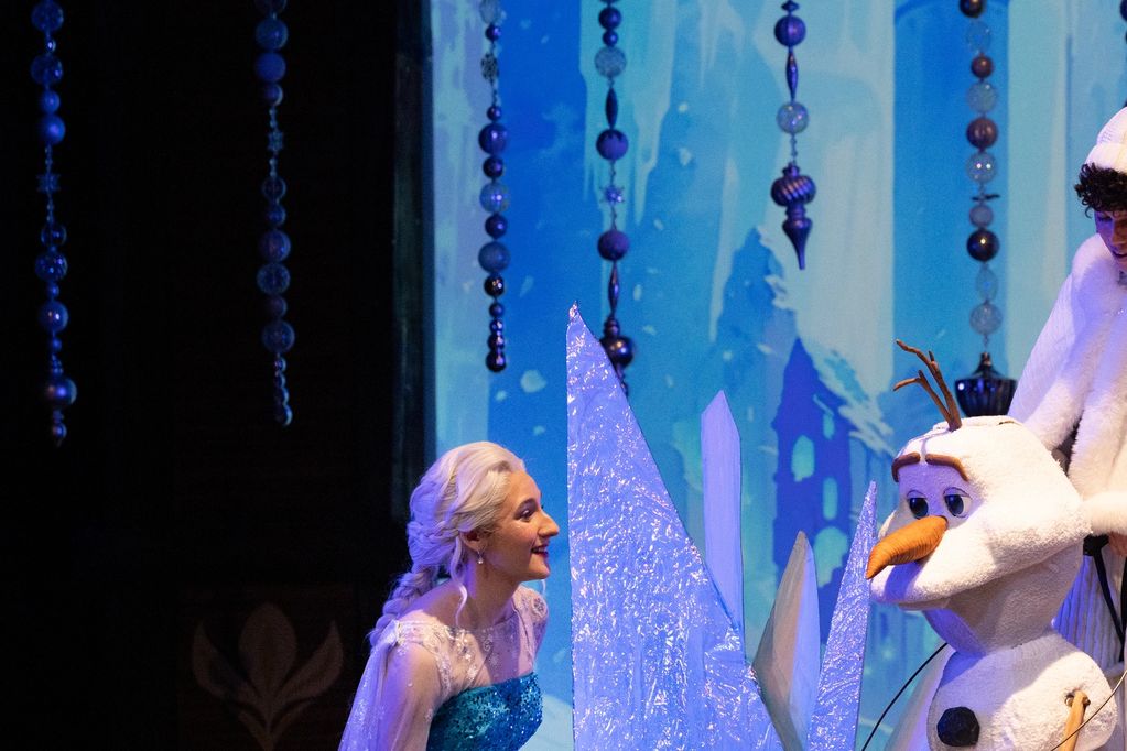 Woman in blue dress interacting with Olaf from Frozen.