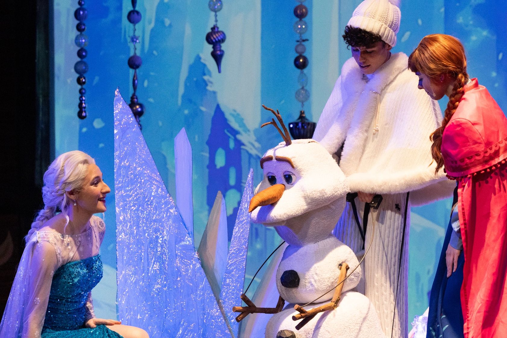 Woman in blue dress interacting with Olaf from Frozen.