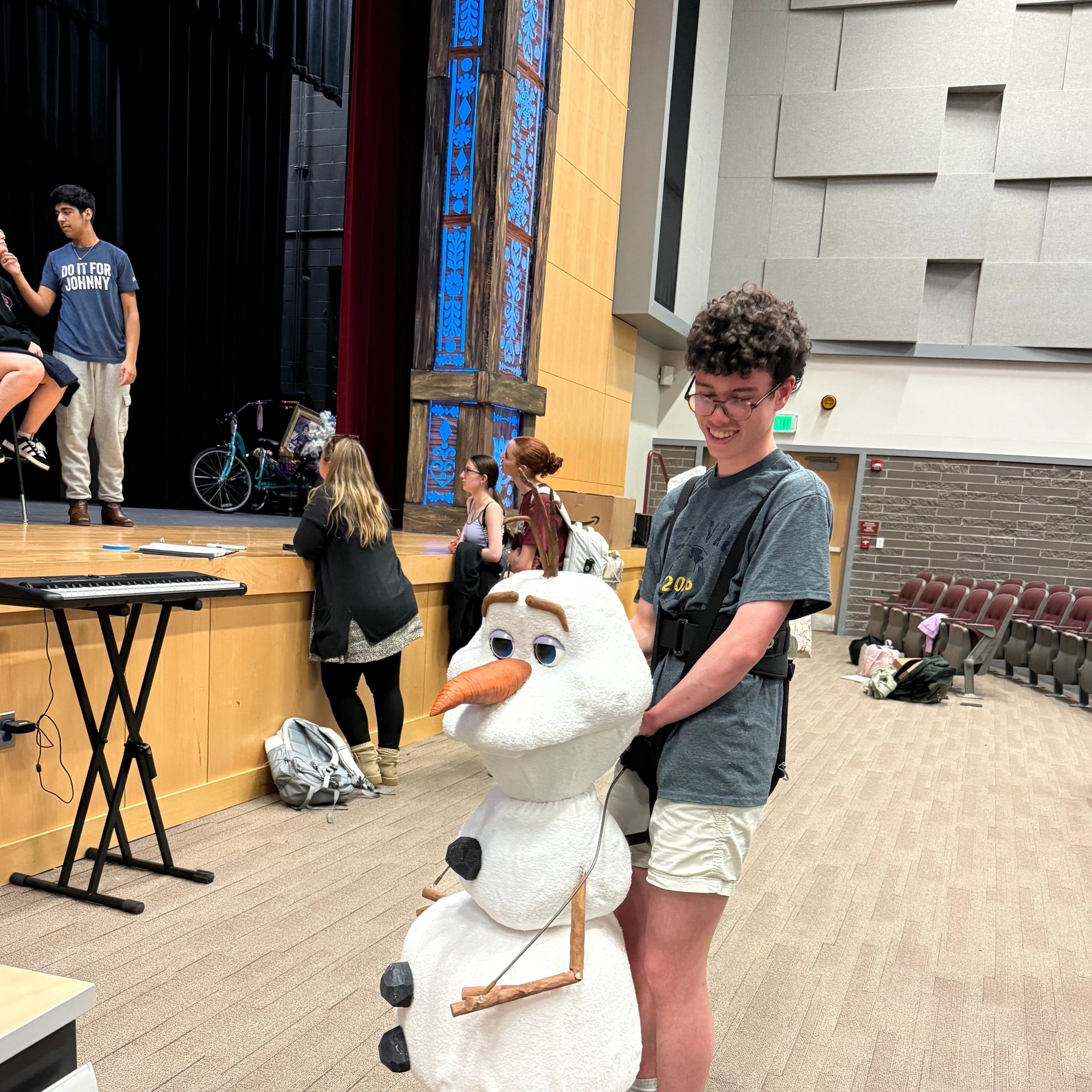 Young man operating a snowman puppet indoors.