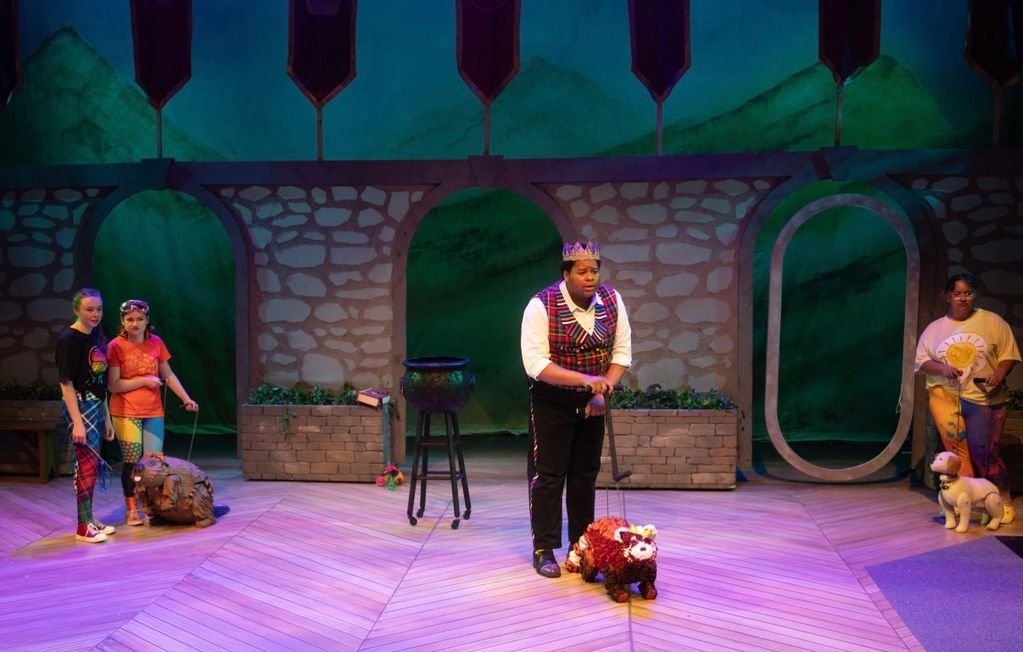Actors perform a play with animal puppets on stage.