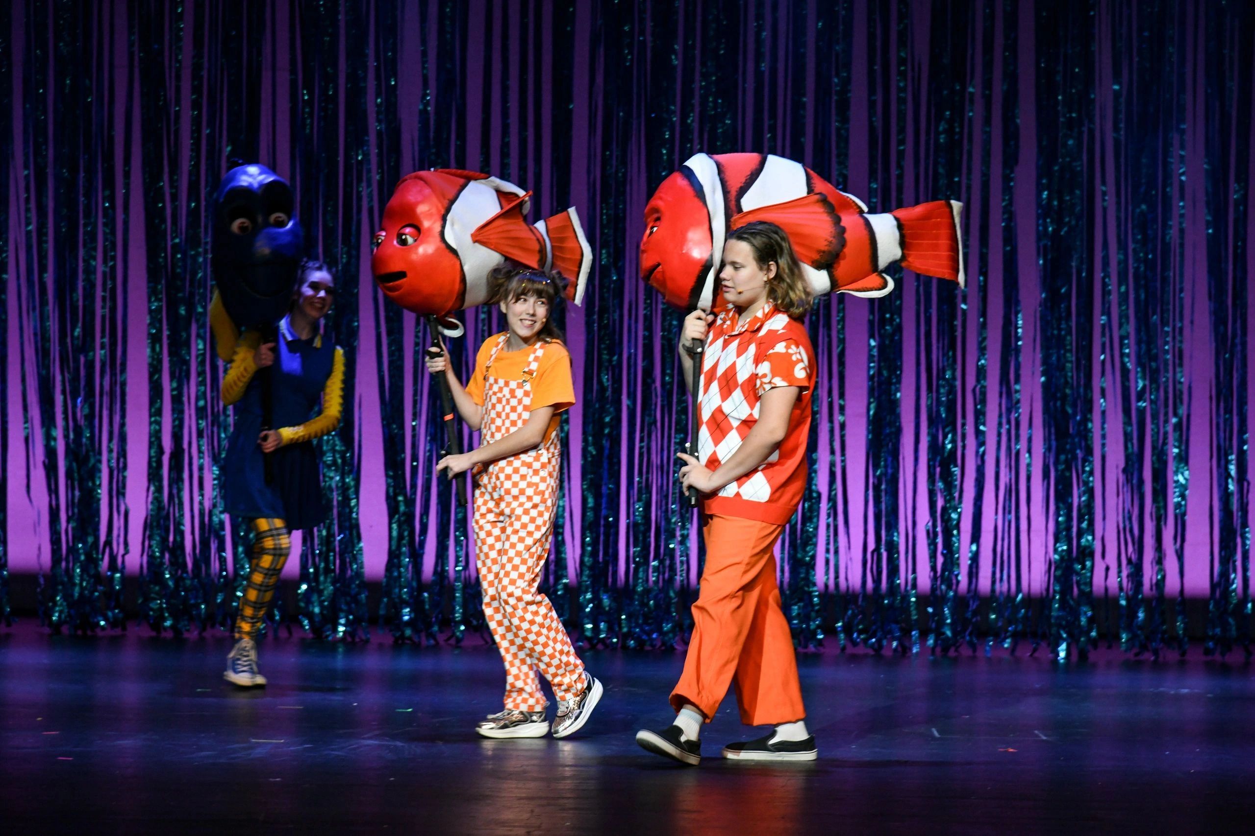 Kids performing on stage with clownfish and blue fish props.