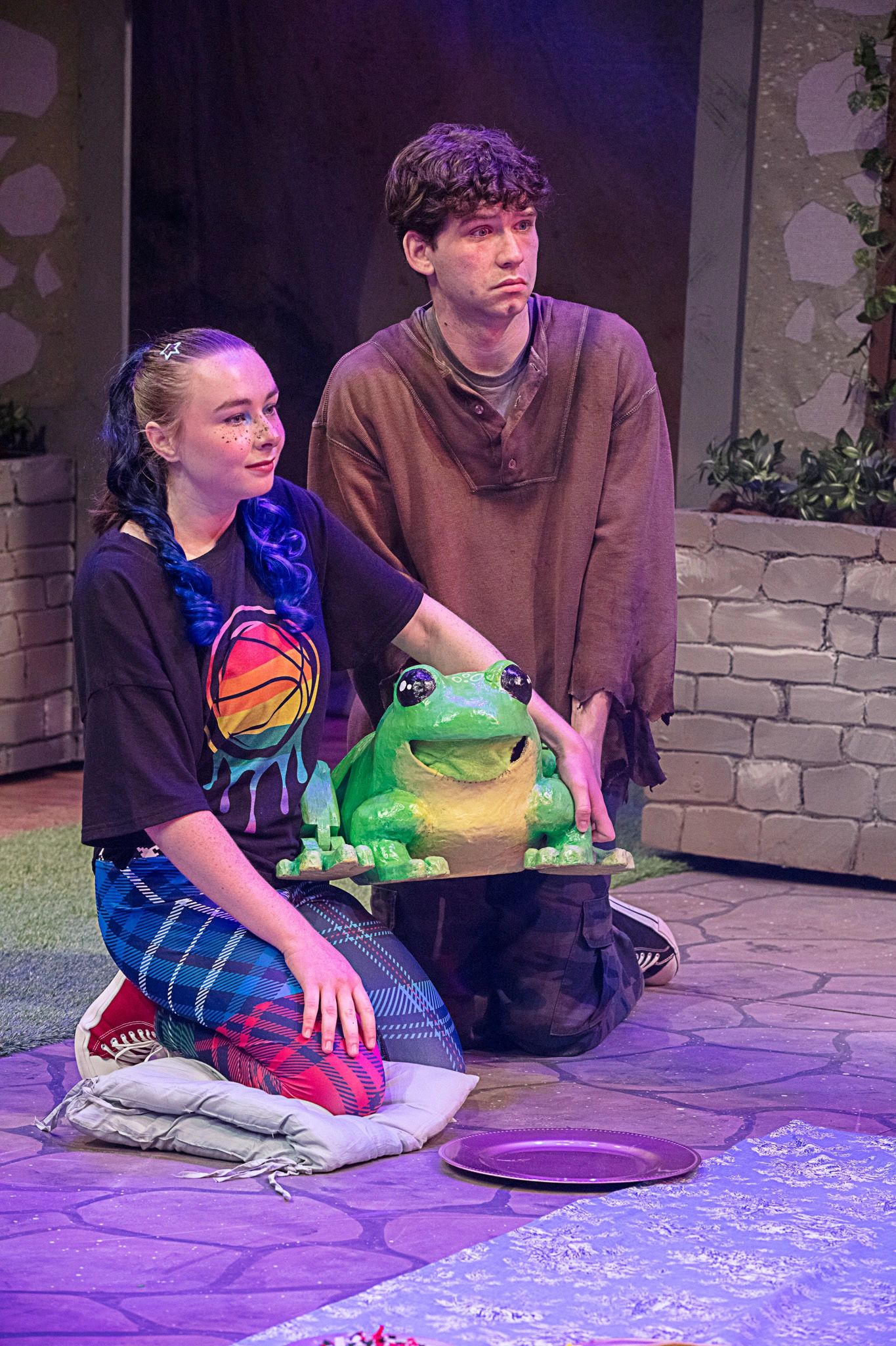 Two actors kneeling holding a green frog prop.