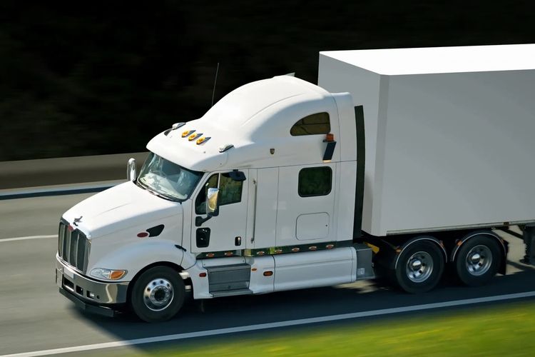 White semi truck hauling a trailer on a US highway — workers' comp, payroll and HR for trucking, con