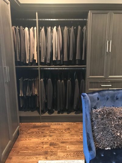 walk in dressing room with a blue sofa. Space for suits jackets, suit pants and ties. wardrobe units