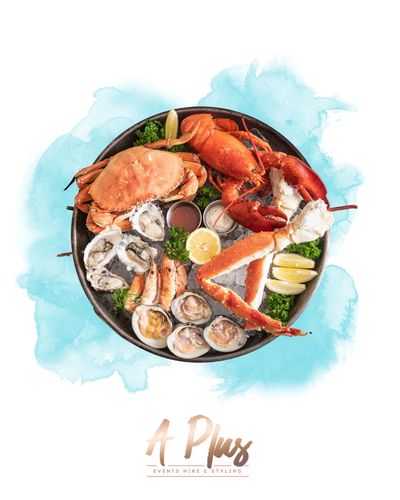 A seafood platter with crab, lobster, oysters, clams, and lemon wedges.