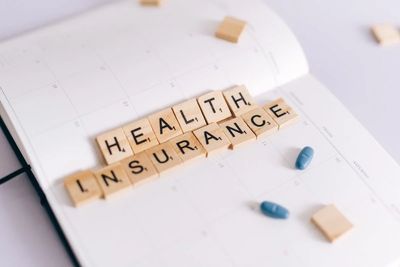 Scrabble tiles spelling ‘Health Insurance,’ representing coverage planning.