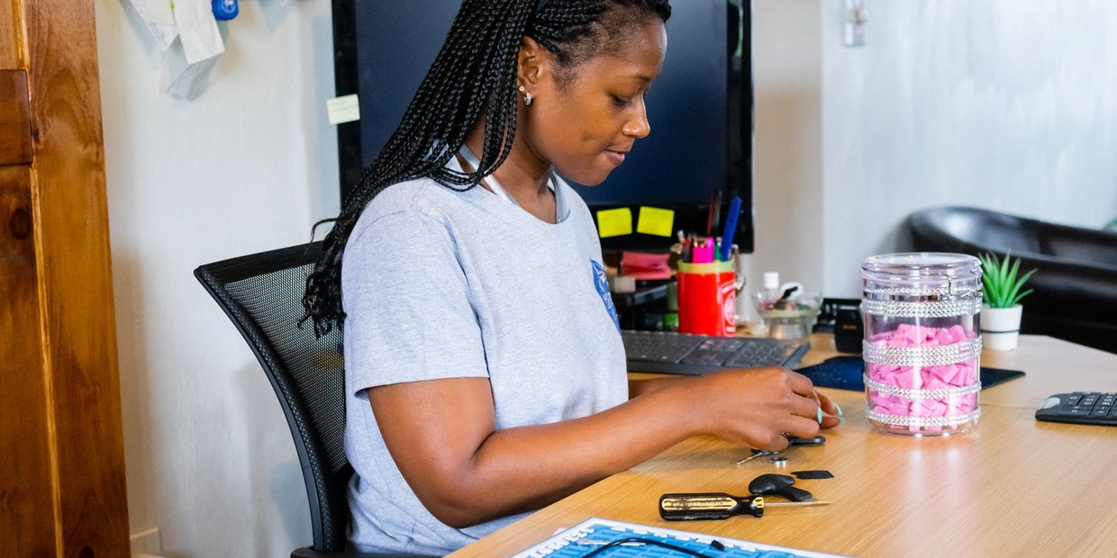 Locksmith technician, sitting at a desk, providing locksmith services by working on auto keys