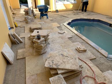 Tiles being installed around a small indoor pool in a yellow-walled room.