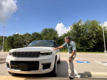 Man touching a white Jeep parked outdoors.