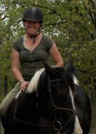 Person smiling while riding a black horse.