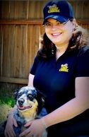 Woman smiling with dog outdoors.
