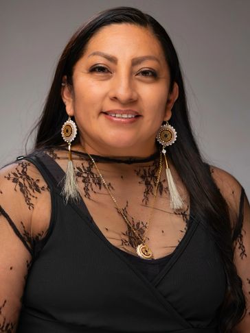 Smiling woman with long dark hair and detailed earrings.