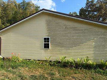 Side of a house showing half cleaned and half dirty siding.