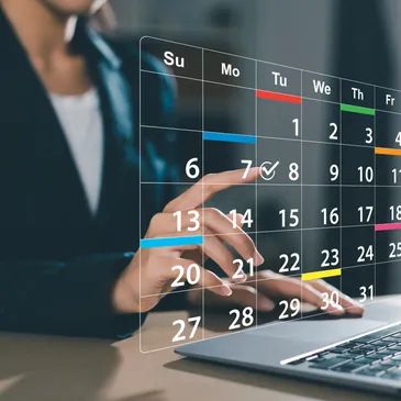 A person interacting with a transparent digital calendar above a laptop.