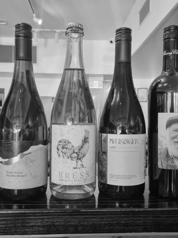 A row of five diverse wine bottles on a wooden surface.