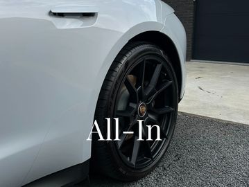 Close-up of a sleek white sports car wheel with black rims and "All-In" text overlay.