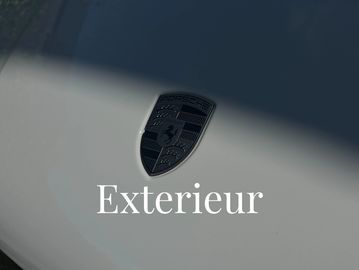 Close-up of a Porsche logo on a smooth car surface with the word 'Exterieur'.