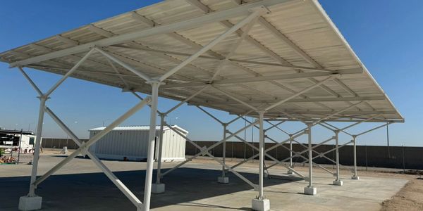 White metal carport structure under clear blue sky on concrete.
