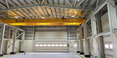 Interior view of an industrial warehouse with a yellow overhead crane.