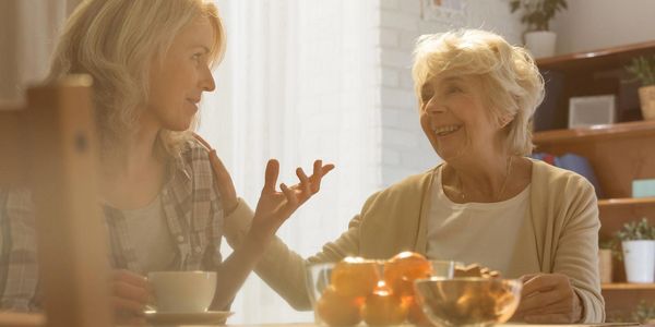 Adult daughter catching up with elderly mom in the kitchen