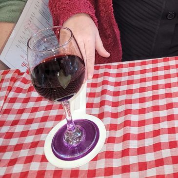 Our founder, Sharon, having a glass of red wine and using a colourful EziFind Coaster that is white 