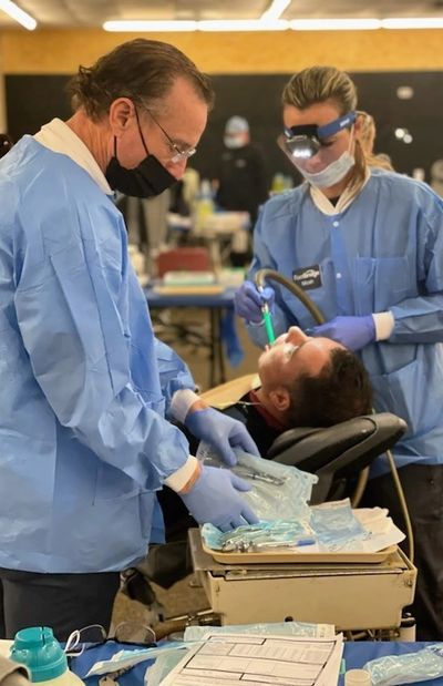 Two dentists treating a patient in a clinic.