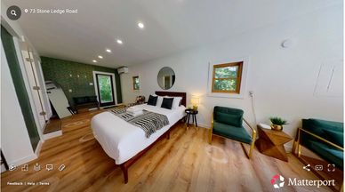 Modern bedroom with green accent chairs and wooden flooring.